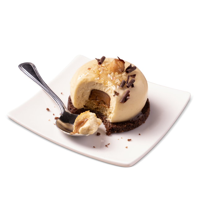 Kupolasti karamel mousse na čokoladnoj keksnoj podlozi, s lješnjacima i čokoladnim strugotinama, zagrizen