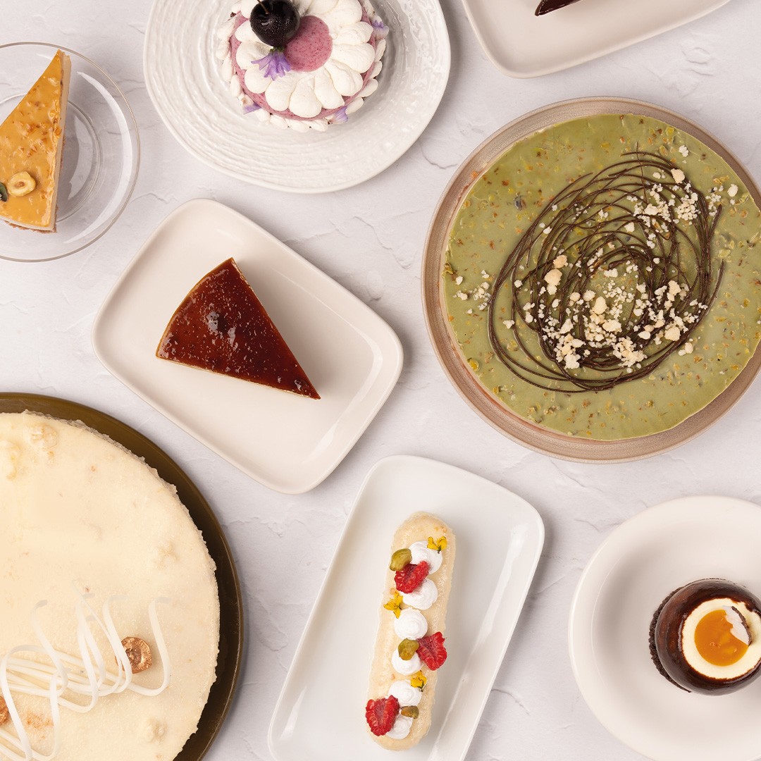 Pogled odozgo na desertе: cheesecake, flan, pistacija torta, eclair i čašice s čokoladnim mousseom