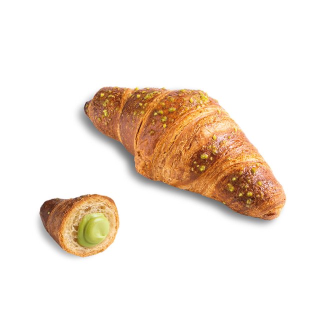 Zlatni croissant posut mrvicama pistacija, manji komad je prerezan i otkriva zeleni krem od pistacija.